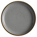 An Acopa Keystone granite gray stoneware coupe plate with a speckled rim.