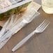 A Visions heavy weight clear plastic fork wrapped in plastic next to a plastic container of salad.