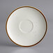 A white stoneware saucer with brown specks on the rim.