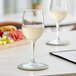 Two Acopa Select Flora wine glasses filled with white wine on a table