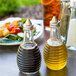 A Tablecraft beehive oil and vinegar dispenser on a table with a plate of salad.