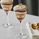 Two Acopa Deco Nick and Nora martini glasses filled with dessert and whipped cream.