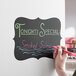 A hand writing on a Choice decorative vinyl chalkboard label with a red marker.