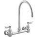 A silver Waterloo wall mount faucet with chrome gooseneck spout and red knobs.