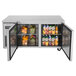 A Turbo Air stainless steel undercounter refrigerator with a shelf of fruit and drinks including oranges.