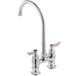 A silver Waterloo deck-mount faucet with red knobs.
