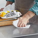 A hand using a WipesPlus table wipe to clean a table.