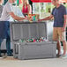 Two men standing next to a CaterGator outdoor cooler full of cans.