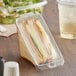 A Choice clear PET tamper-evident sandwich container with a sandwich inside on a table in a deli.