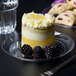 A Fineline clear plastic plate with a white-frosted cake topped with blackberries.