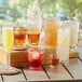 Choice plastic highball glasses filled with a variety of drinks on a table.
