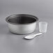 A stainless steel bowl with a white plastic spoon and cup inside.