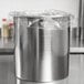 An Avantco stainless steel bain marie pot with plastic wrap on top.