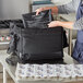 A person using a Vesture black thermal bag with a LavaPac heating element to prepare food.