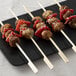 Bamboo paddle skewers with meatballs, peppers, and onions.