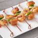 A plate of shrimp skewers with green onions and peppers on a table.
