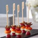 A tray of food on bamboo skewers with a stack of bamboo food picks.