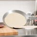 A person using a Matfer Bourgeat carbon steel crepe pan to cook a crepe.