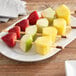 A plate of fruit skewers with strawberries, apples, and pineapple.