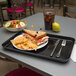 A Carlisle black market tray with a sandwich, chips, and a plate of food on it.