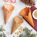A Konery pumpkin spice waffle cone stand with three cones filled with candy on a marble surface.