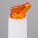 A white plastic Carlisle Store 'N Pour container with an orange spout and cap.