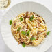 A white plate of Barilla Fettuccine pasta with mushrooms and parmesan cheese.