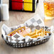 A black check Choice basket liner with a hot dog and fries in it.