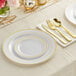 A table setting with gold plastic plates and classic flatware, including forks, spoons, and knives.