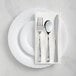 A Visions white plastic plate with silver Classic flatware on it.
