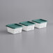 Three white plastic containers with green square lids.