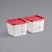 Two square white plastic Carlisle food storage containers with red lids.