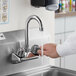 A person washing their hands in a sink using a gooseneck faucet with a white surface.
