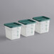 A row of Carlisle white square plastic food storage containers with green lids.