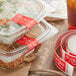 Two plastic containers of food with red TamperSafe labels on the table.