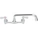 A chrome 12" wall mounted swing spout swivel faucet with two handles.