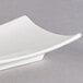 A close up of a white rectangular porcelain plate with a curved edge.