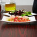 An Arcoroc rectangular porcelain plate with shrimp salad on a table.