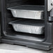 The front of a black Cambro Ultra Pan Carrier with food trays inside.