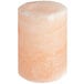 A Himalayan salt shot glass filled with a pink liquid on a white surface.