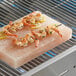 A grill with shrimp cooking on a Himalayan salt slab.