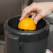 A hand squeezing an orange into a Robot Coupe Cuisine Kit.