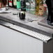 A stainless steel beer drip tray mounted under a bar counter.