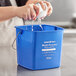 A person washing a Noble Products blue cleaning pail.