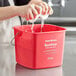 A person washing their hands in a red Noble Products sanitizing pail.