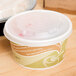 A white Eco-Products Evolution World paper soup cup with a lid containing food on a table.