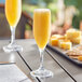 An Acopa Endure Tritan plastic champagne flute filled with orange juice on a table.