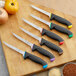 A group of Schraf boning knives with black handles on a cutting board.