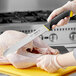 A hand holding a Schraf serrated slicing knife with a yellow handle cutting a turkey.