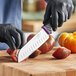 A person in black gloves using a Schraf Santoku knife to cut tomatoes.